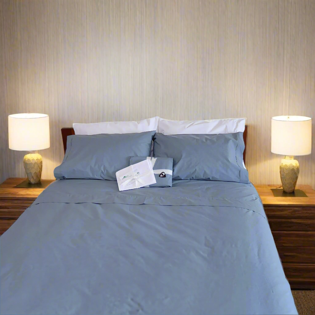 SleepFROg blue organic cotton flat sheet, duvet cover with blue& white pillowcases on bed. 